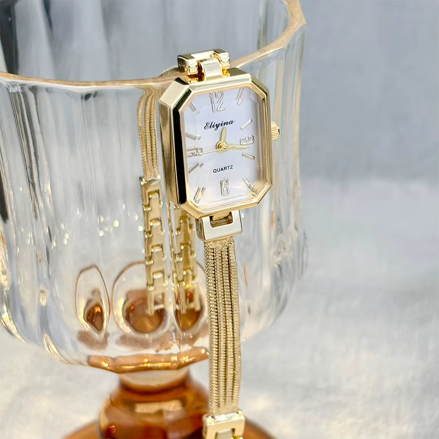 Montre-bracelet rectangulaire dorée pour femme avec chaînes à pampilles, un accessoire délicat