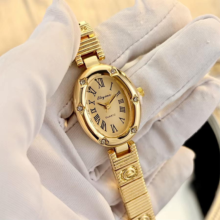 Montre dorée élégante pour femme avec cadran ovale, motifs étoiles et bracelet E-Charmed